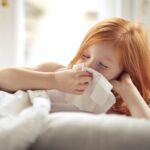 A girl with a dust allergy wiping her running nose